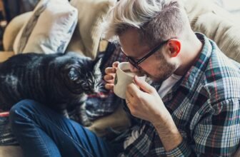 man, sofa, coffee, mug, coffee cup, cup, animal, drink, drinking coffee, morning coffee, coffee break, caffeine, drinking, adult, cat, pet, couch, indoors, leisure, portrait, seat, sitting